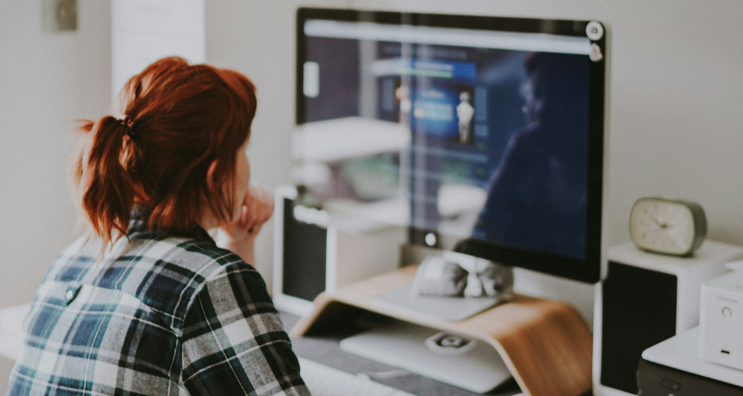 Woman in front of iMac at desk doing coding work