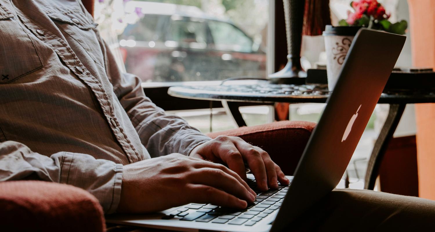 Man sitting and typing on computer in coffee shop