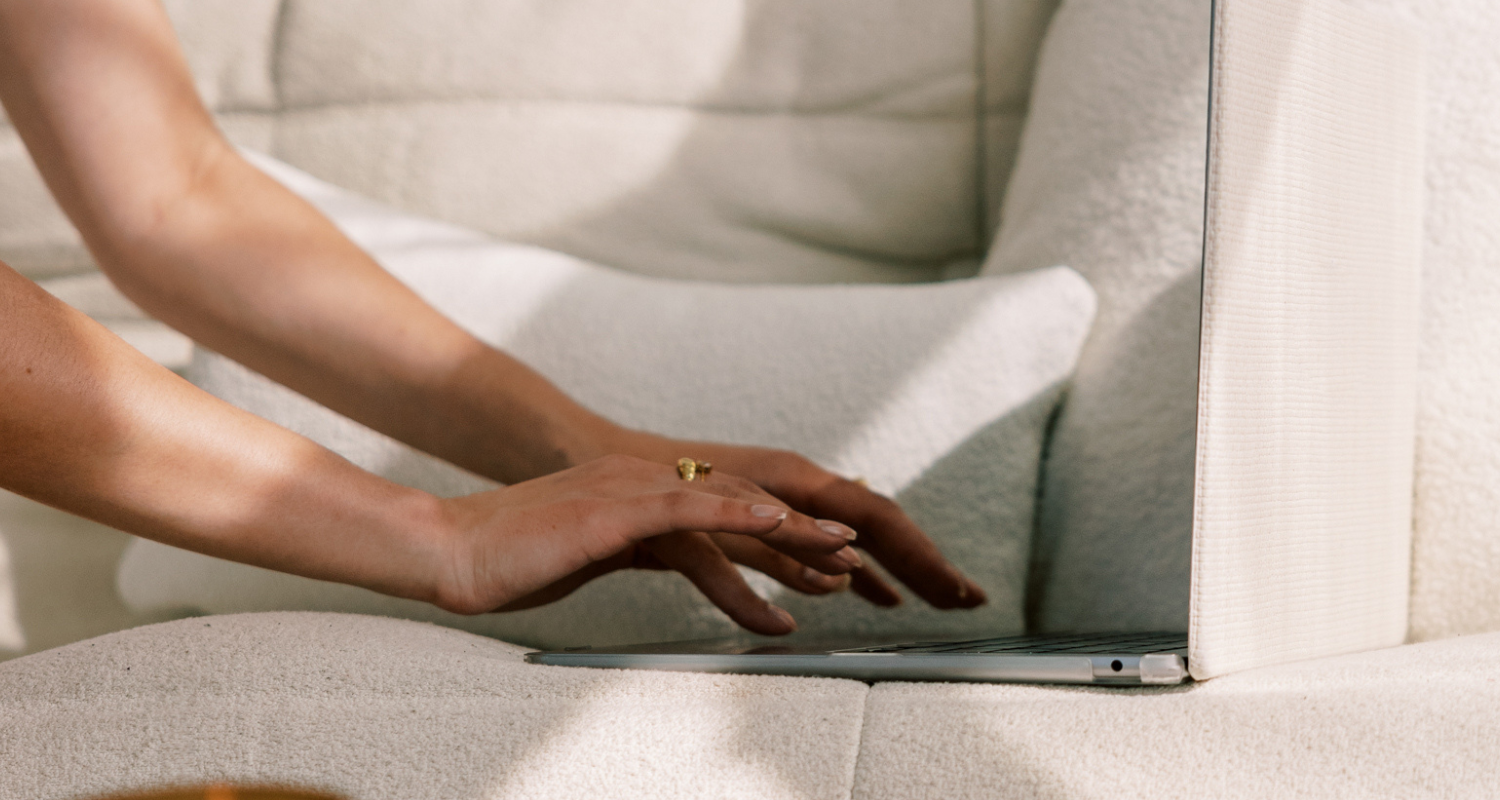 Woman sitting on couch with hands and laptop in frame