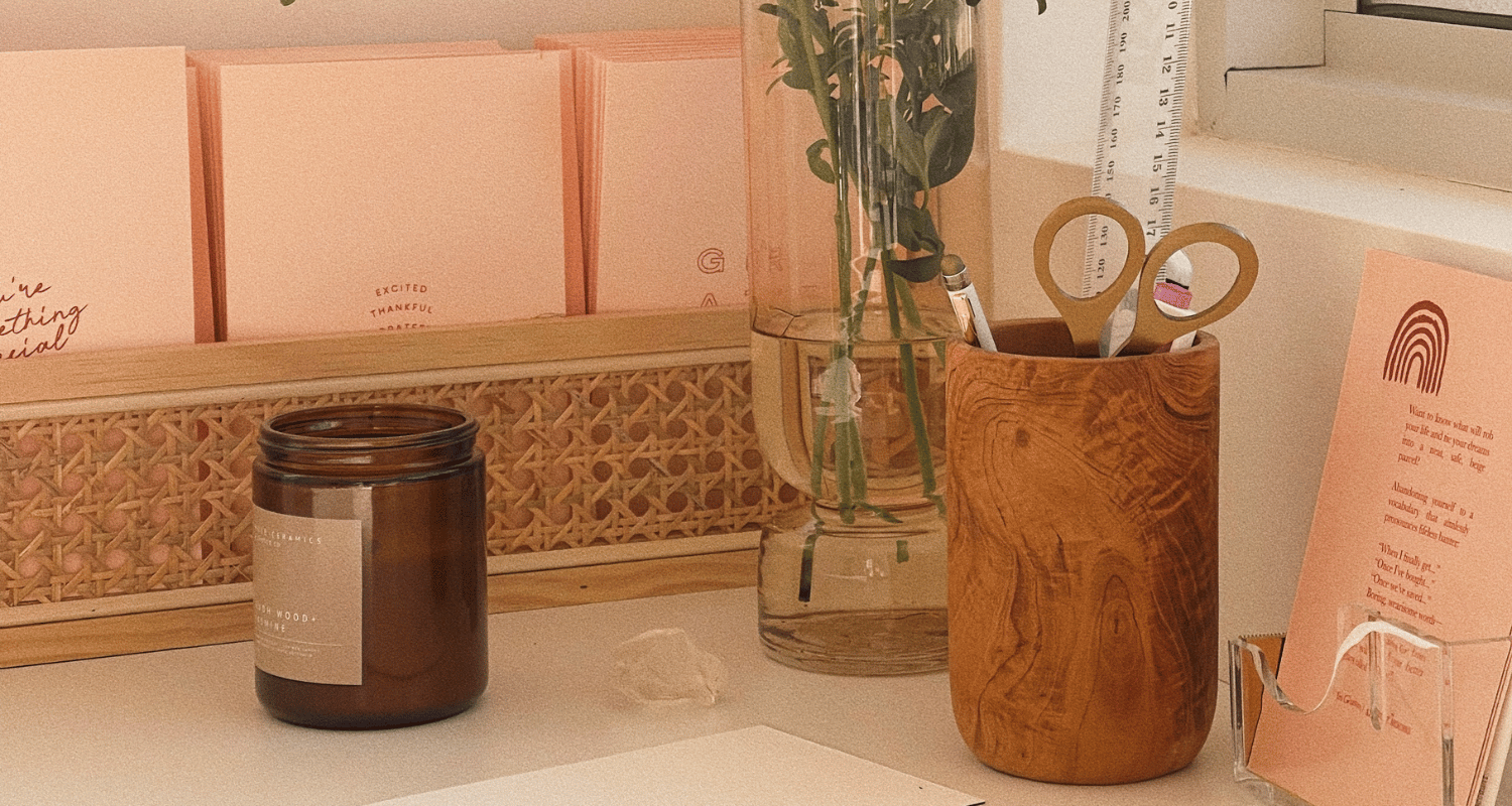 Small business candles with packaging materials on desk with flowers and scissors and candle